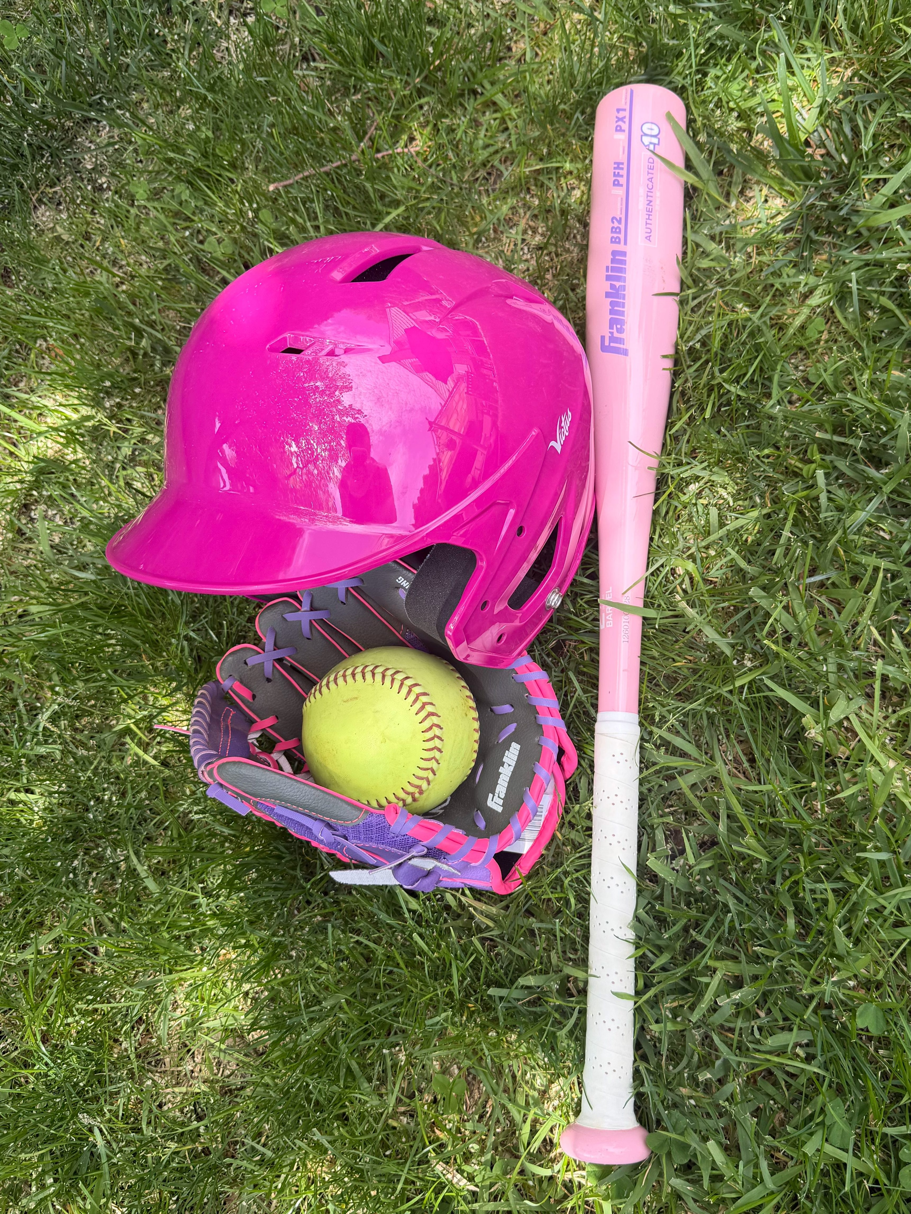 Pink youth T-ball gear including helmet, glove, softball, and bat