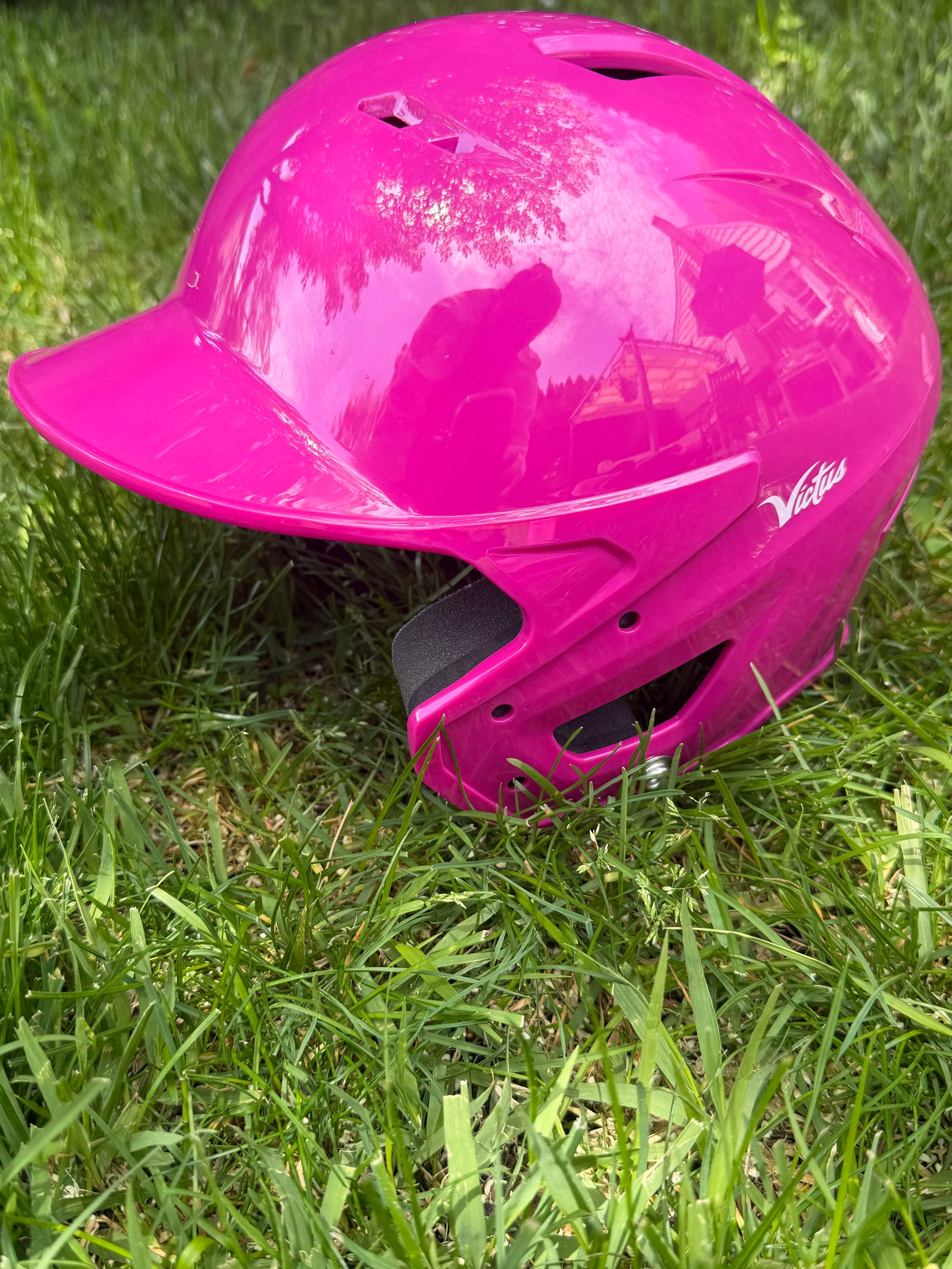 Bright pink youth T-ball helmet on grass
