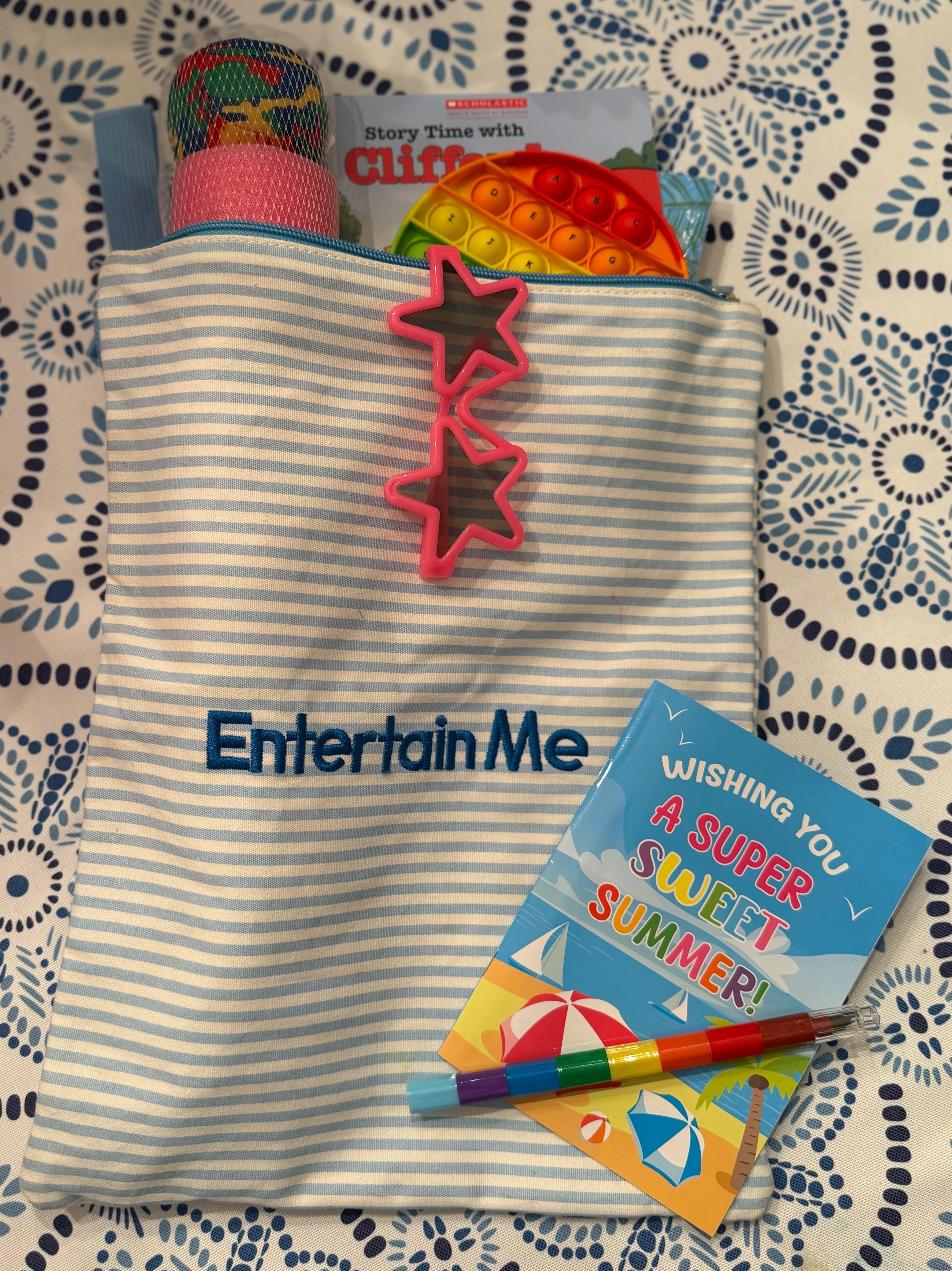Entertain Me pouch packed with small books, toys, and activities for kids to use during pool breaks.